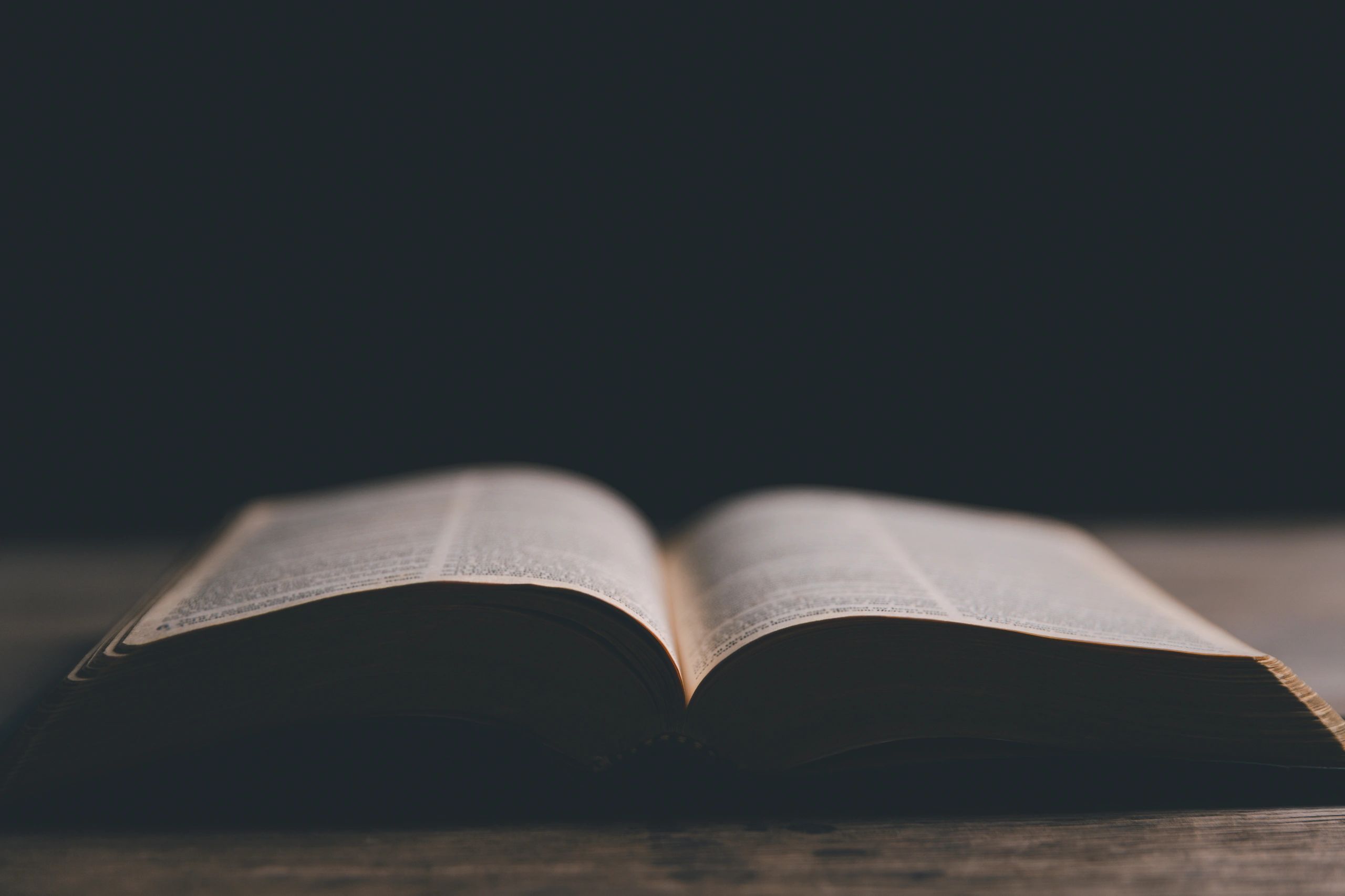 Hands in prayer beside an open Bible